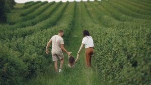 Happy family walking together through a lush green field enjoying nature and togetherness.
