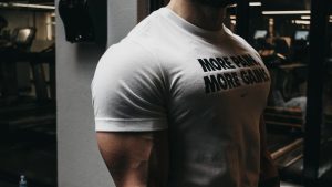 Close-up of a muscular man in a t-shirt training in an indoor gym setting.